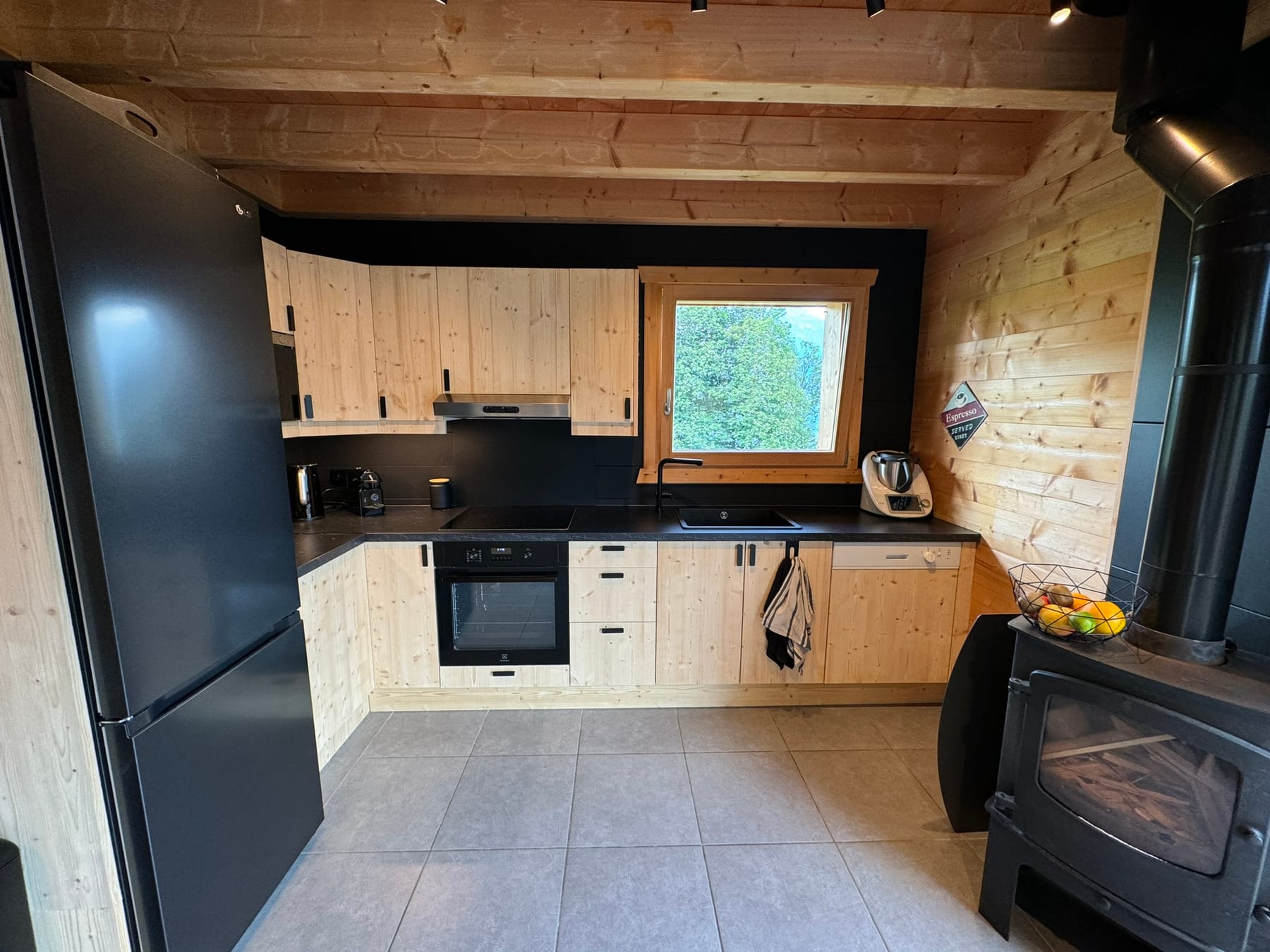 Cuisine en bois clair, électroménager noir, poêle